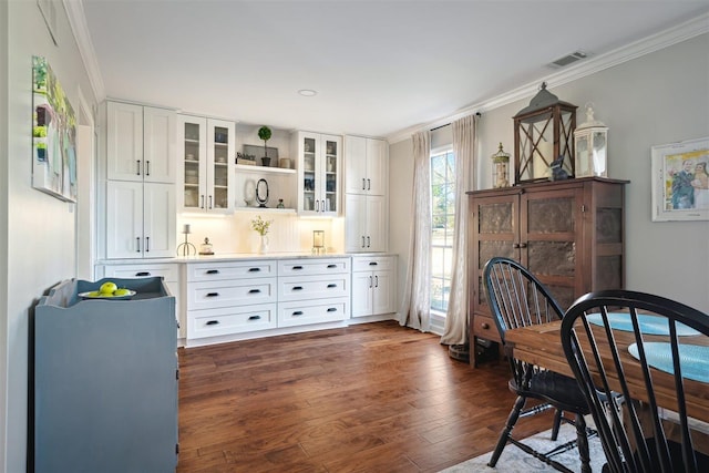 dining space with dark wood finished floors, crown molding, and visible vents