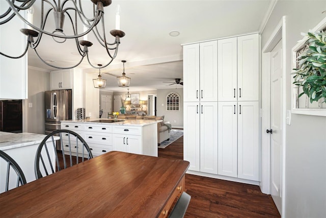 dining area with dark wood-type flooring, crown molding, and ceiling fan with notable chandelier