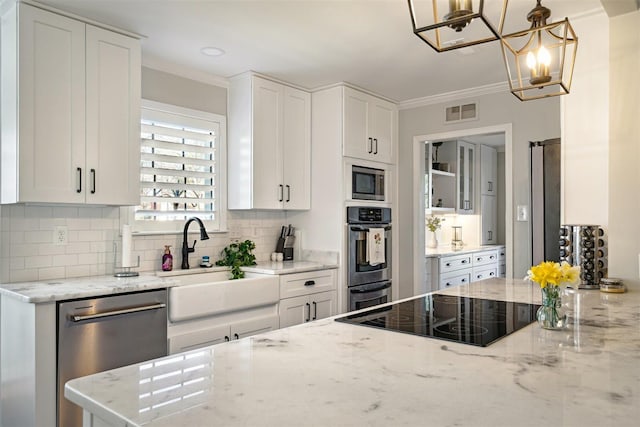 kitchen featuring visible vents, ornamental molding, a sink, appliances with stainless steel finishes, and a notable chandelier