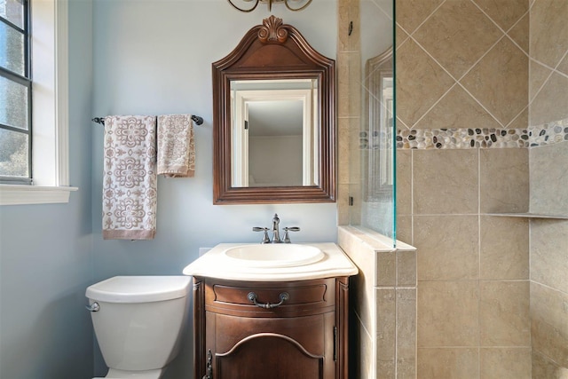 full bathroom featuring a tile shower, toilet, and vanity