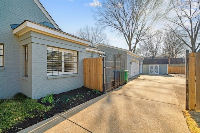 view of side of property with a garage, brick siding, an outdoor structure, and fence