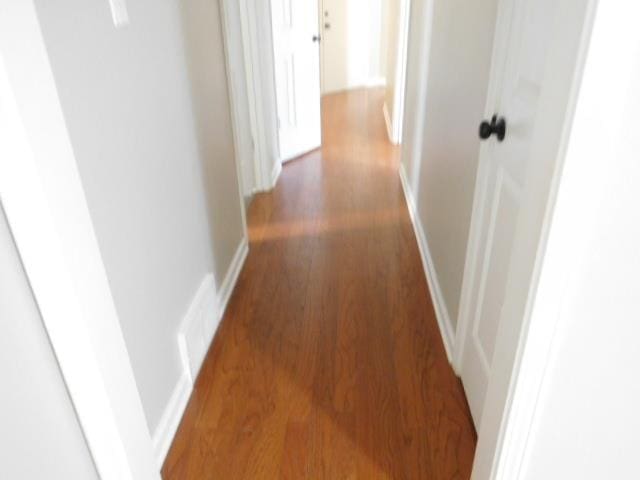 corridor featuring baseboards and wood finished floors