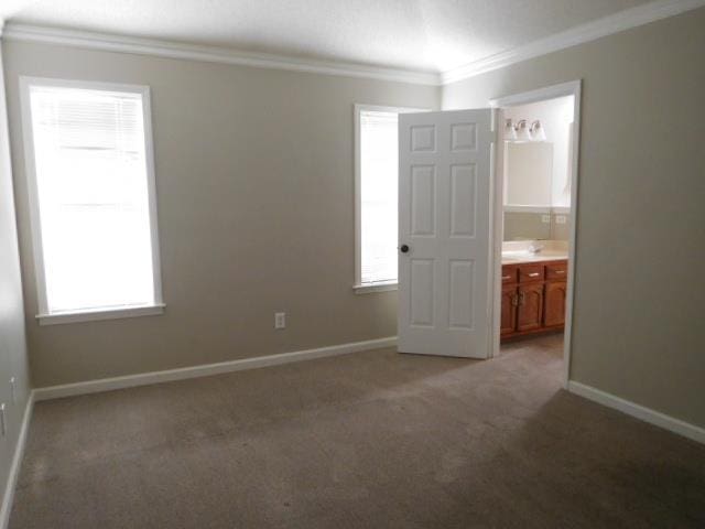 unfurnished bedroom with baseboards, multiple windows, light carpet, and ornamental molding