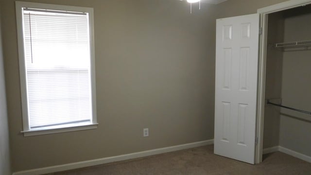 unfurnished bedroom featuring light colored carpet, baseboards, and a closet