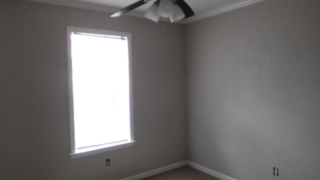 spare room with a ceiling fan and baseboards