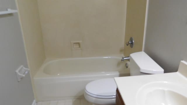 full bath with a sink, toilet,  shower combination, and tile patterned flooring