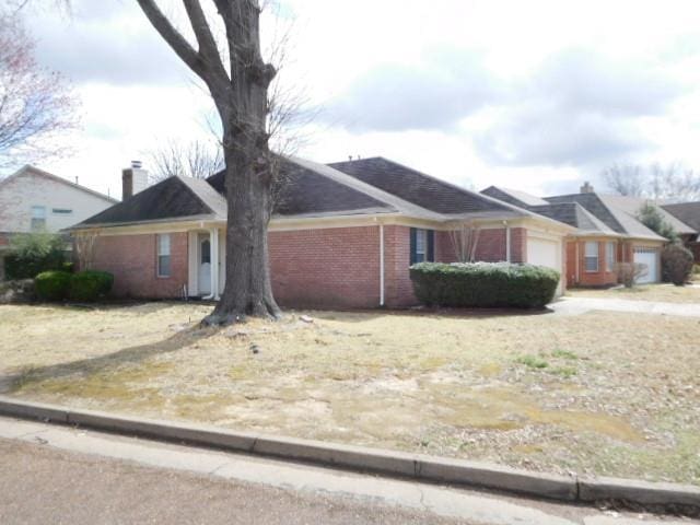 view of side of property featuring brick siding, an attached garage, and driveway