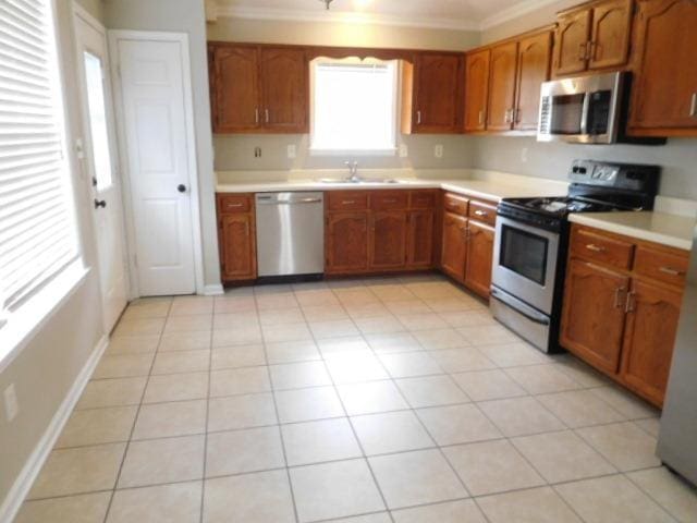 kitchen featuring a sink, stainless steel appliances, brown cabinets, and light countertops