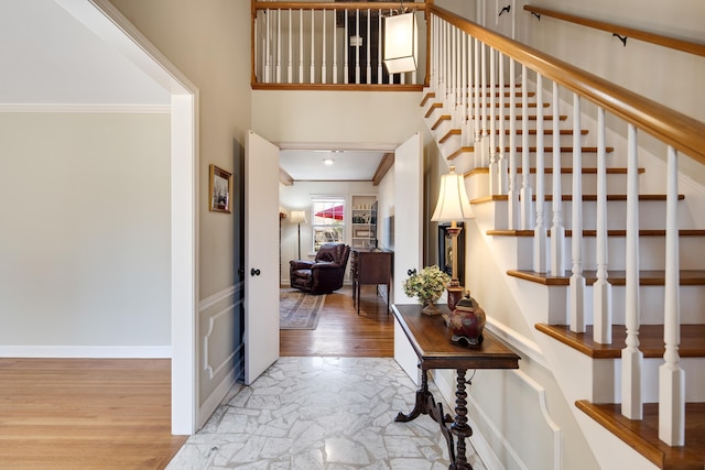 hall featuring stairs, crown molding, wood finished floors, and baseboards