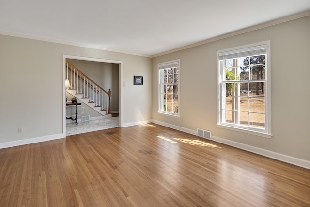 empty room featuring visible vents, baseboards, wood finished floors, and stairs