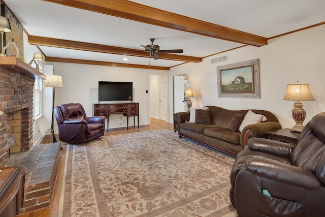 living room featuring visible vents, ceiling fan, ornamental molding, beam ceiling, and wood finished floors