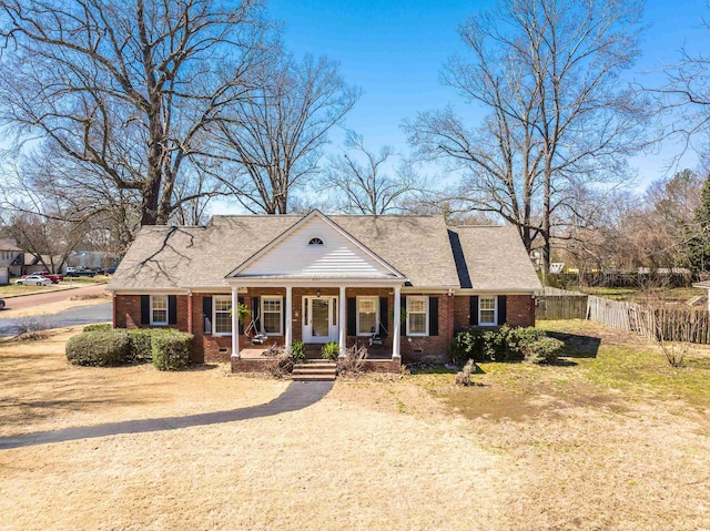 greek revival inspired property with a porch, fence, and brick siding