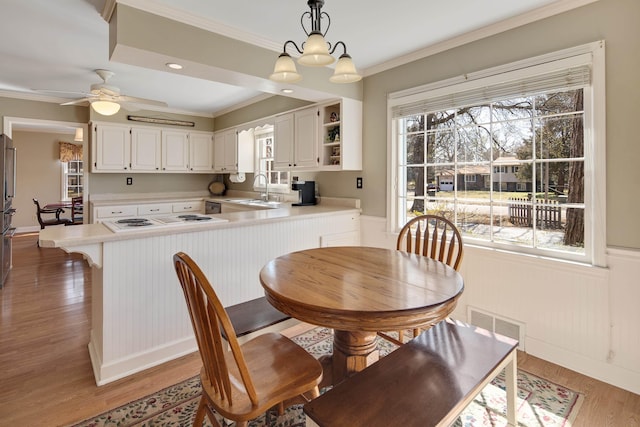 dining area featuring visible vents, a ceiling fan, light wood-style floors, and ornamental molding