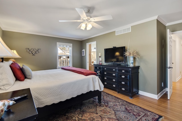 bedroom featuring visible vents, baseboards, ornamental molding, light wood-style floors, and a ceiling fan