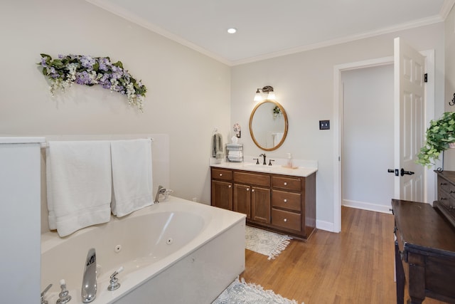 bathroom with vanity, a jetted tub, wood finished floors, and ornamental molding