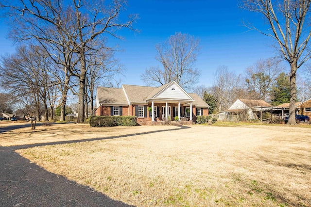 view of front of house with brick siding, covered porch, and a front lawn