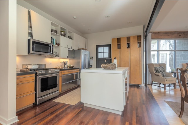 kitchen with open shelves, a kitchen island, appliances with stainless steel finishes, white cabinets, and dark wood-style flooring