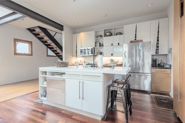 kitchen featuring a kitchen bar, open shelves, high quality fridge, and dark wood-style flooring