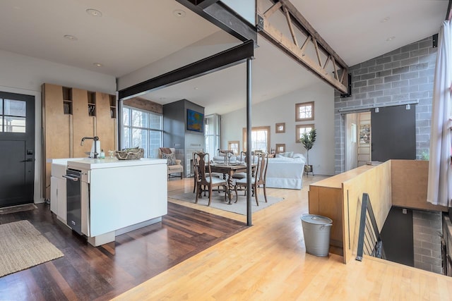 kitchen featuring lofted ceiling with beams, a sink, dark wood-type flooring, light countertops, and open floor plan