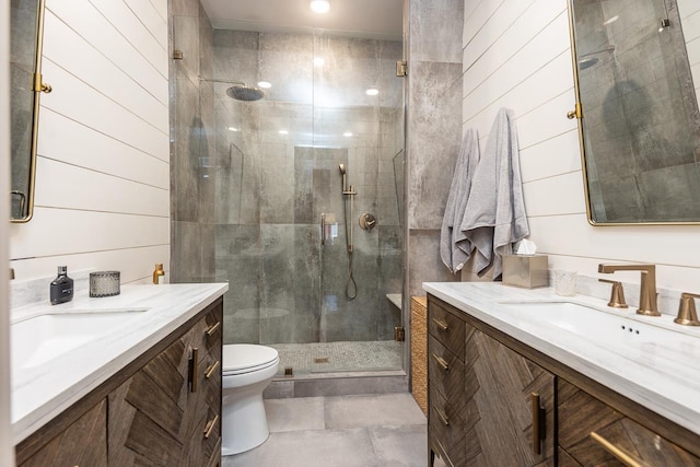 bathroom with toilet, two vanities, a stall shower, and a sink