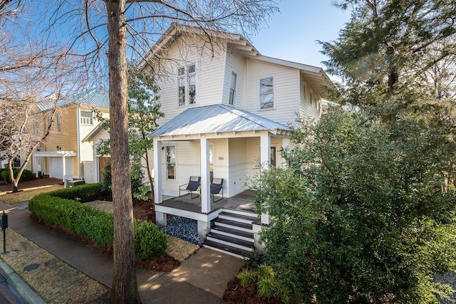 american foursquare style home with covered porch and metal roof