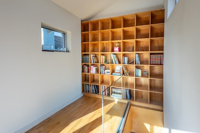 interior space with baseboards, wood finished floors, and vaulted ceiling