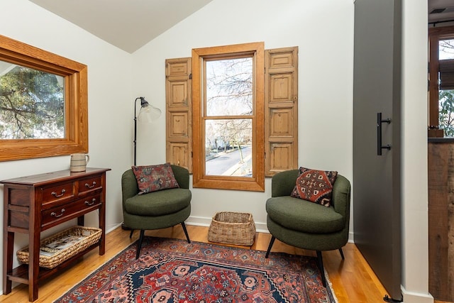 sitting room featuring baseboards, lofted ceiling, and wood finished floors