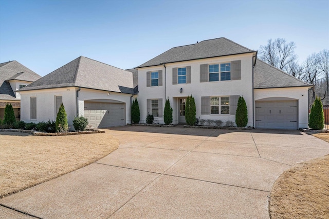 view of front of home featuring stucco siding, an attached garage, driveway, and roof with shingles