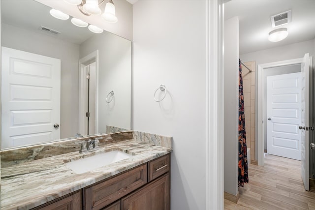 bathroom with vanity, a shower with shower curtain, wood finished floors, and visible vents