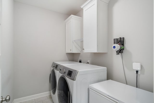 washroom with washer and clothes dryer, cabinet space, baseboards, and light tile patterned flooring