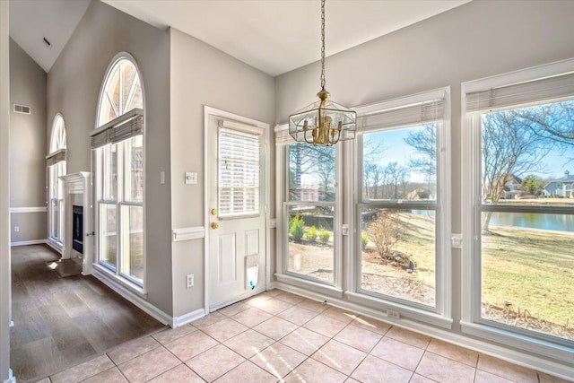 interior space with a notable chandelier, visible vents, a healthy amount of sunlight, and light tile patterned floors