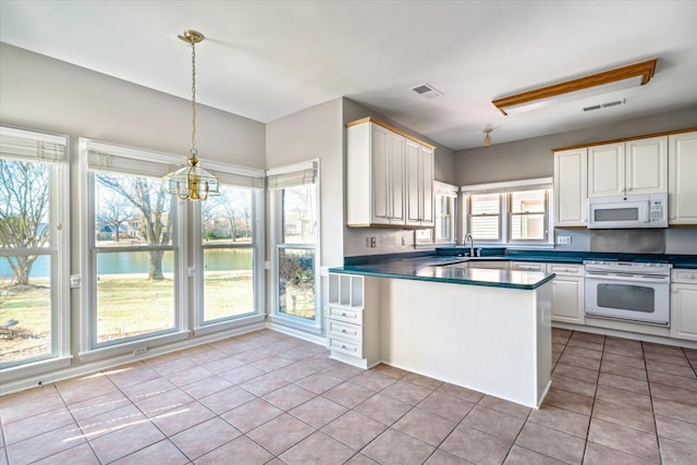 kitchen featuring white appliances, light tile patterned floors, dark countertops, and visible vents