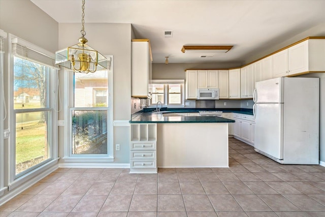 kitchen featuring dark countertops, white appliances, a peninsula, light tile patterned floors, and a chandelier