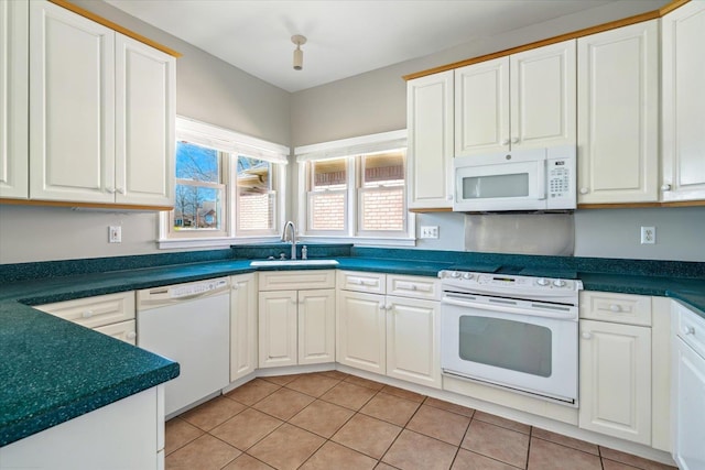 kitchen with dark countertops, light tile patterned flooring, white appliances, white cabinetry, and a sink