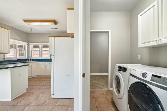 laundry area with light tile patterned floors, visible vents, cabinet space, and separate washer and dryer