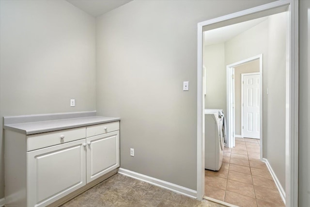 interior space with laundry area, light tile patterned floors, baseboards, and washing machine and clothes dryer