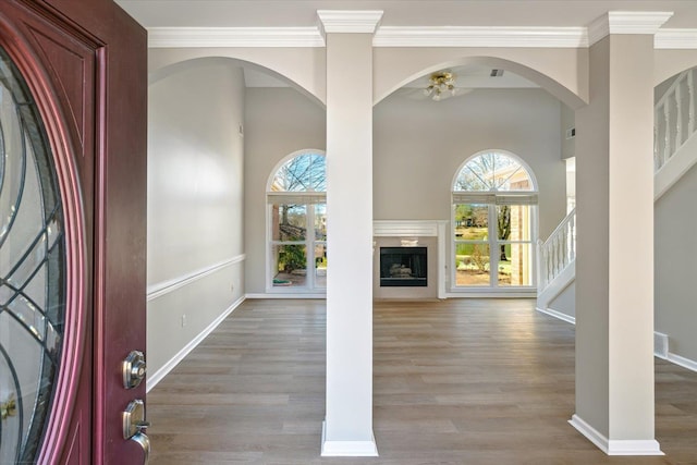 entryway with stairway, wood finished floors, baseboards, ceiling fan, and crown molding