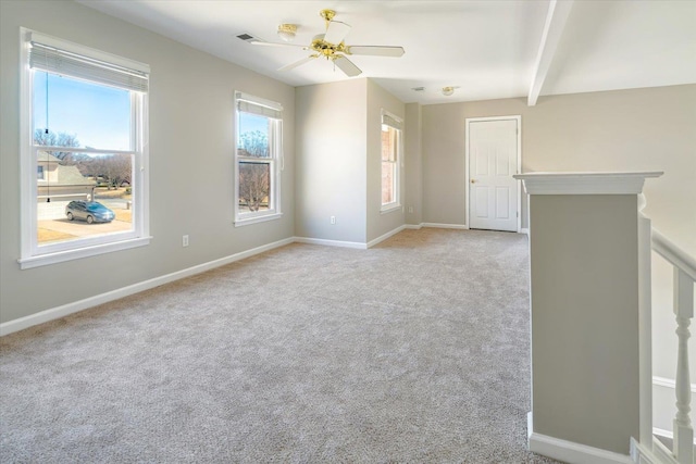 spare room with visible vents, baseboards, ceiling fan, light carpet, and beamed ceiling