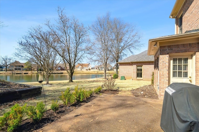 view of patio / terrace featuring grilling area, a residential view, and a water view