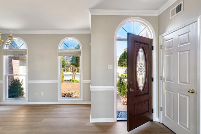 entrance foyer with visible vents, baseboards, wood finished floors, and crown molding