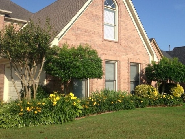 view of side of home with a lawn and brick siding