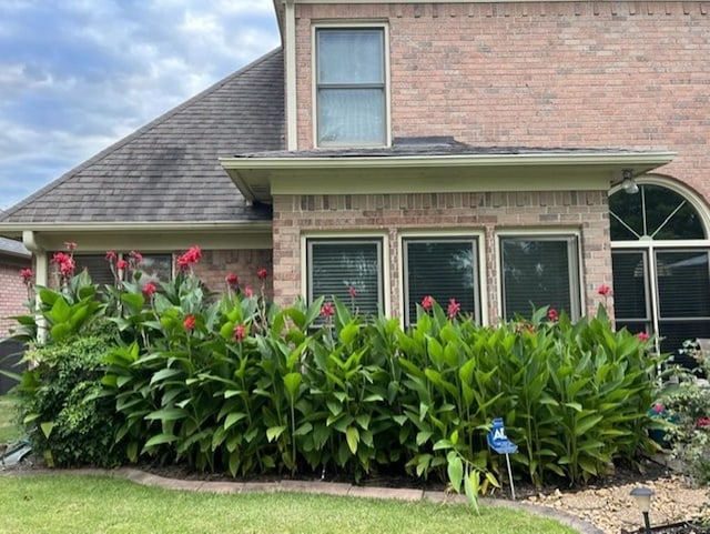 view of home's exterior with brick siding and roof with shingles