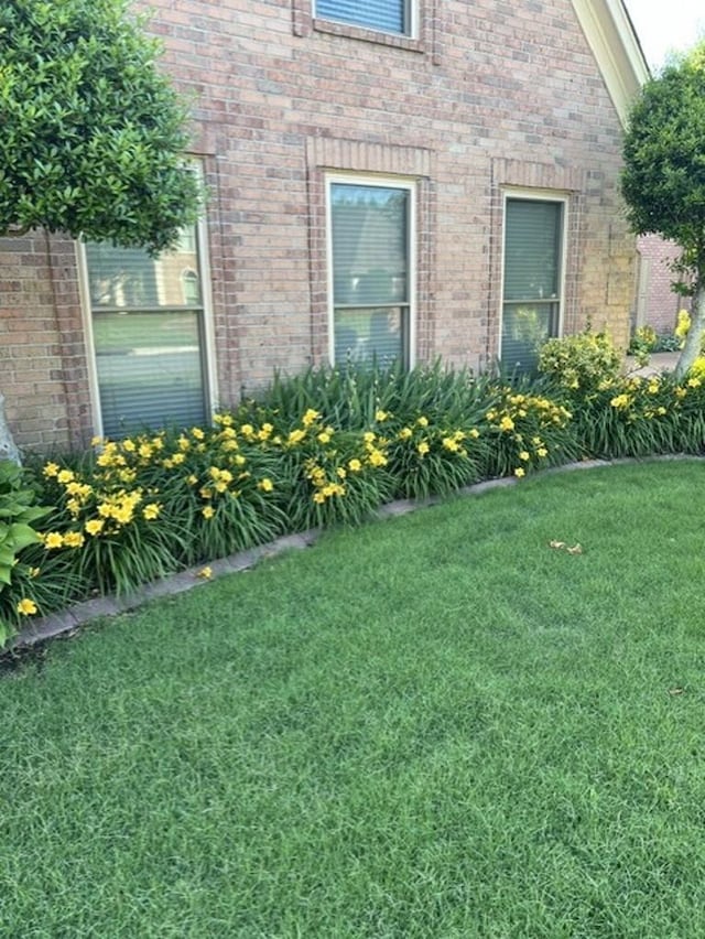 view of side of property with a lawn and brick siding