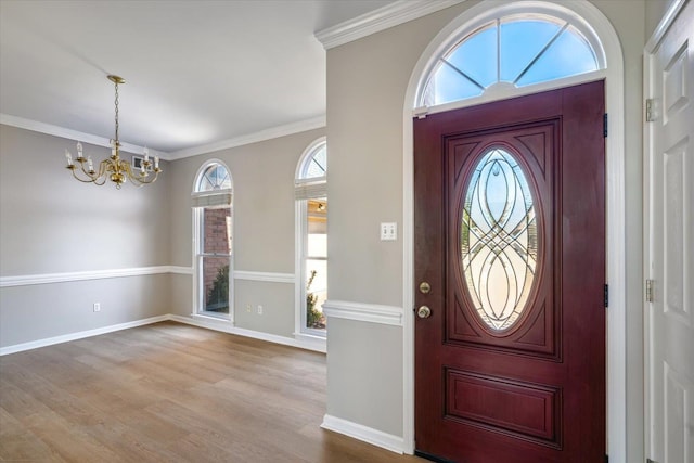 foyer entrance featuring a notable chandelier, wood finished floors, baseboards, and ornamental molding