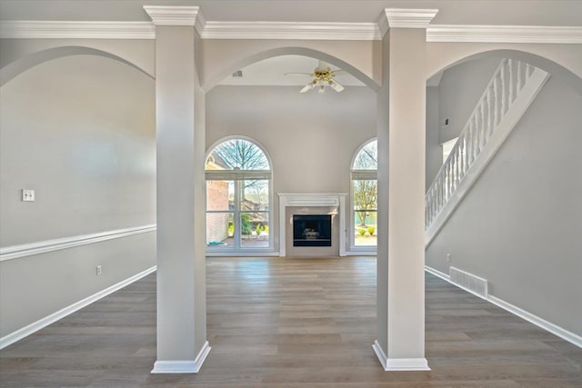 unfurnished living room with wood finished floors, baseboards, visible vents, and ceiling fan