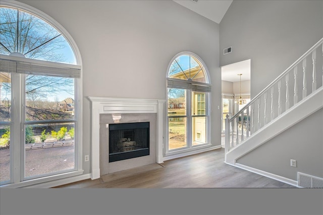 unfurnished living room with visible vents, high vaulted ceiling, wood finished floors, and stairs