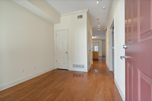 corridor featuring visible vents, baseboards, crown molding, and light wood finished floors