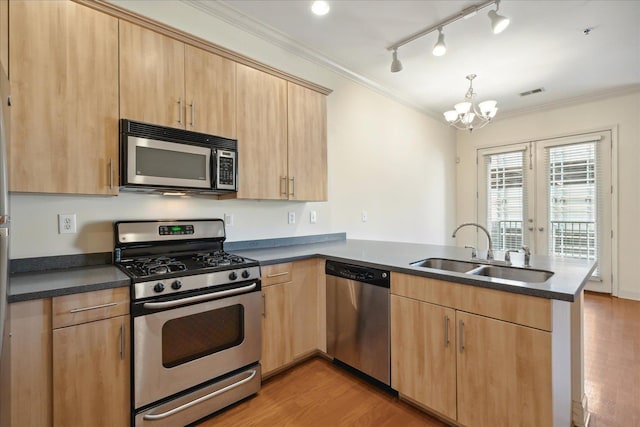 kitchen with a sink, appliances with stainless steel finishes, a peninsula, and light brown cabinetry