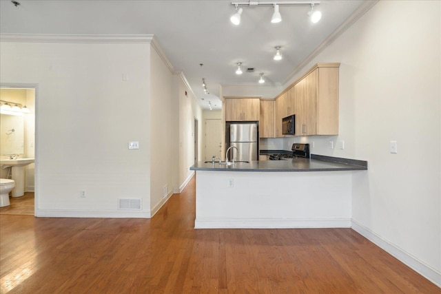 kitchen featuring visible vents, ornamental molding, appliances with stainless steel finishes, a peninsula, and wood finished floors