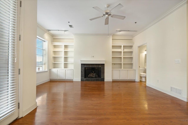 unfurnished living room featuring visible vents, ornamental molding, built in features, and wood finished floors